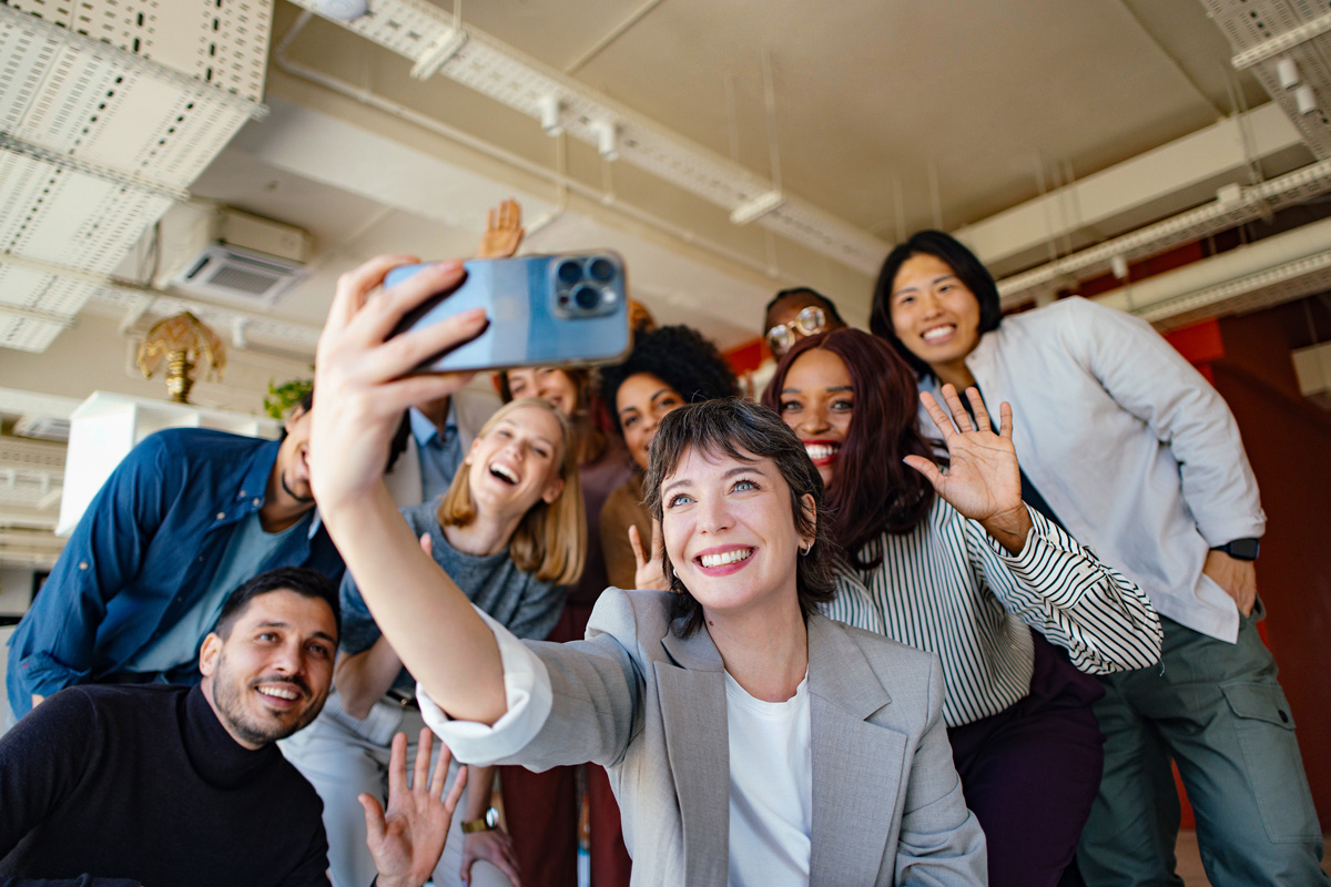 Employer Branding – entspanntes Team fotografiert sich selbst mit dem Handy