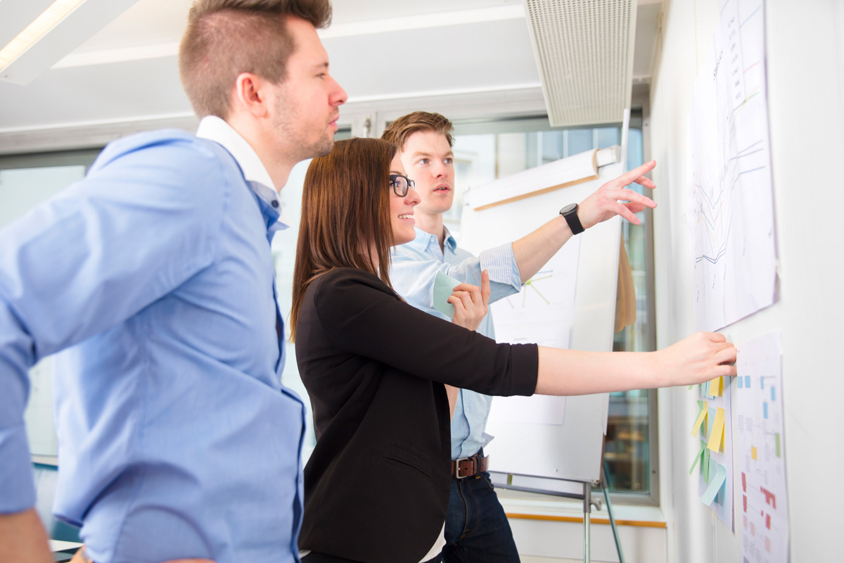 Marke & Kommunikation – Team schaut in eine Richtung auf Notizen am Flip-Chart!